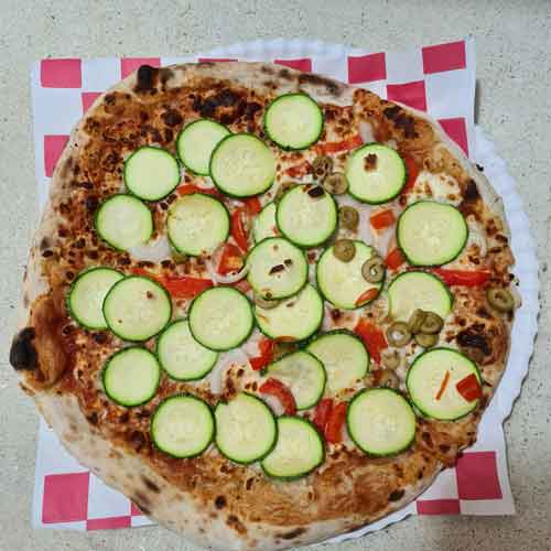 Pizza con salsa de tomate, queso Mozzarella rayado, calabacita, cebolla y queso de cabra